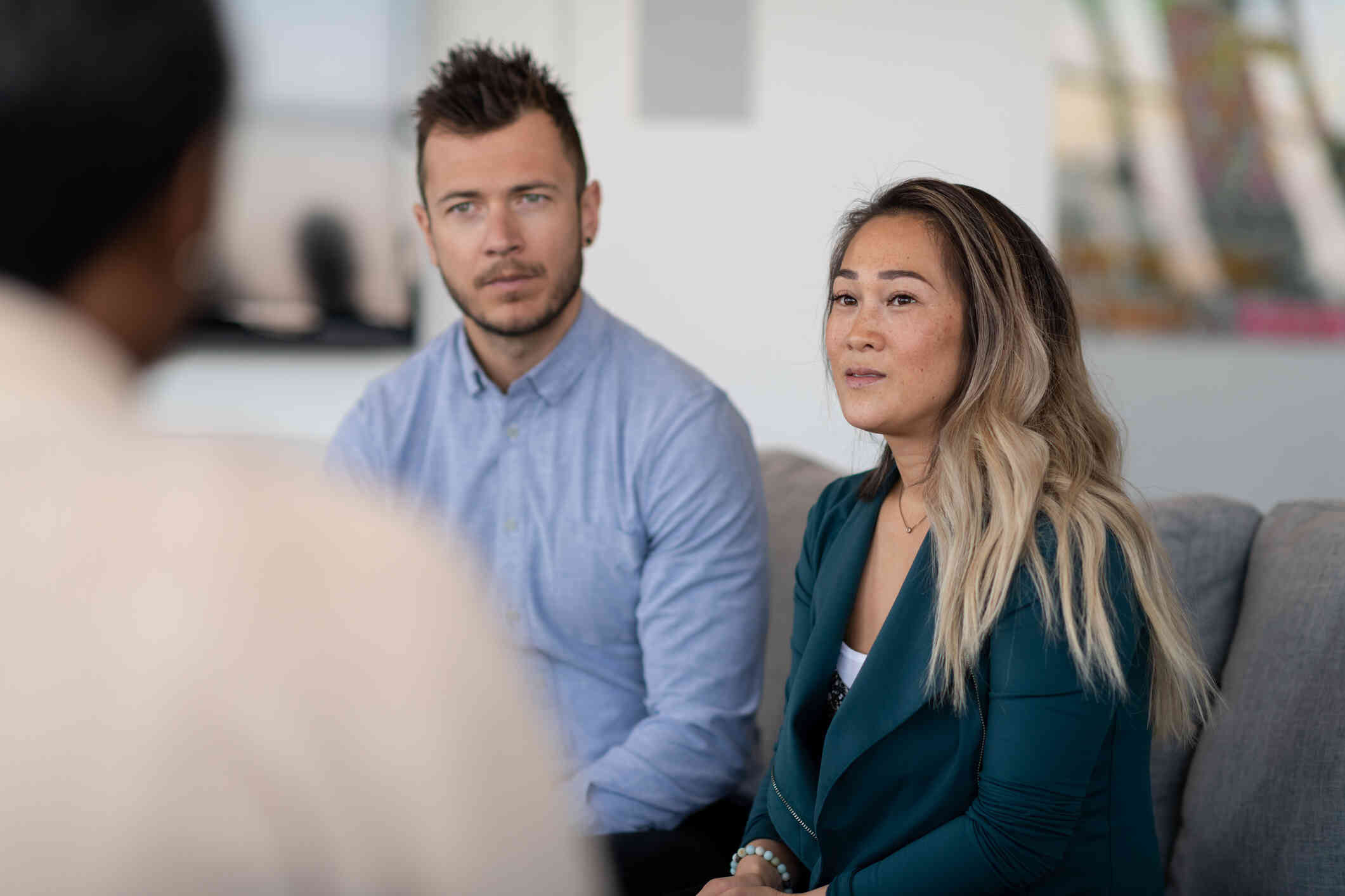 A couple listens intently to a therapist sitting in front of them.